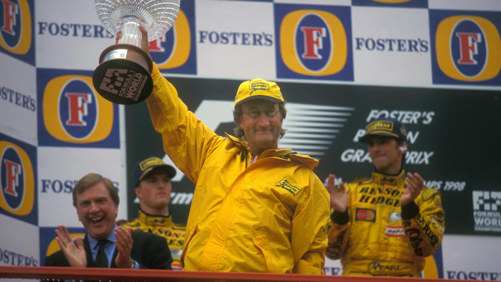 Eddie Jordan holds trophy on podium after Damon Hill won the 1998 Belgian Grand Prix