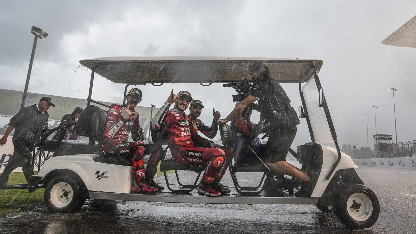 Miguel-Oliveira-Jack-Miller-and-Pecco-Bagnaia-in-a-golf-cart-as-rain-pours-down-after-the-MotoGP-Thai-GP