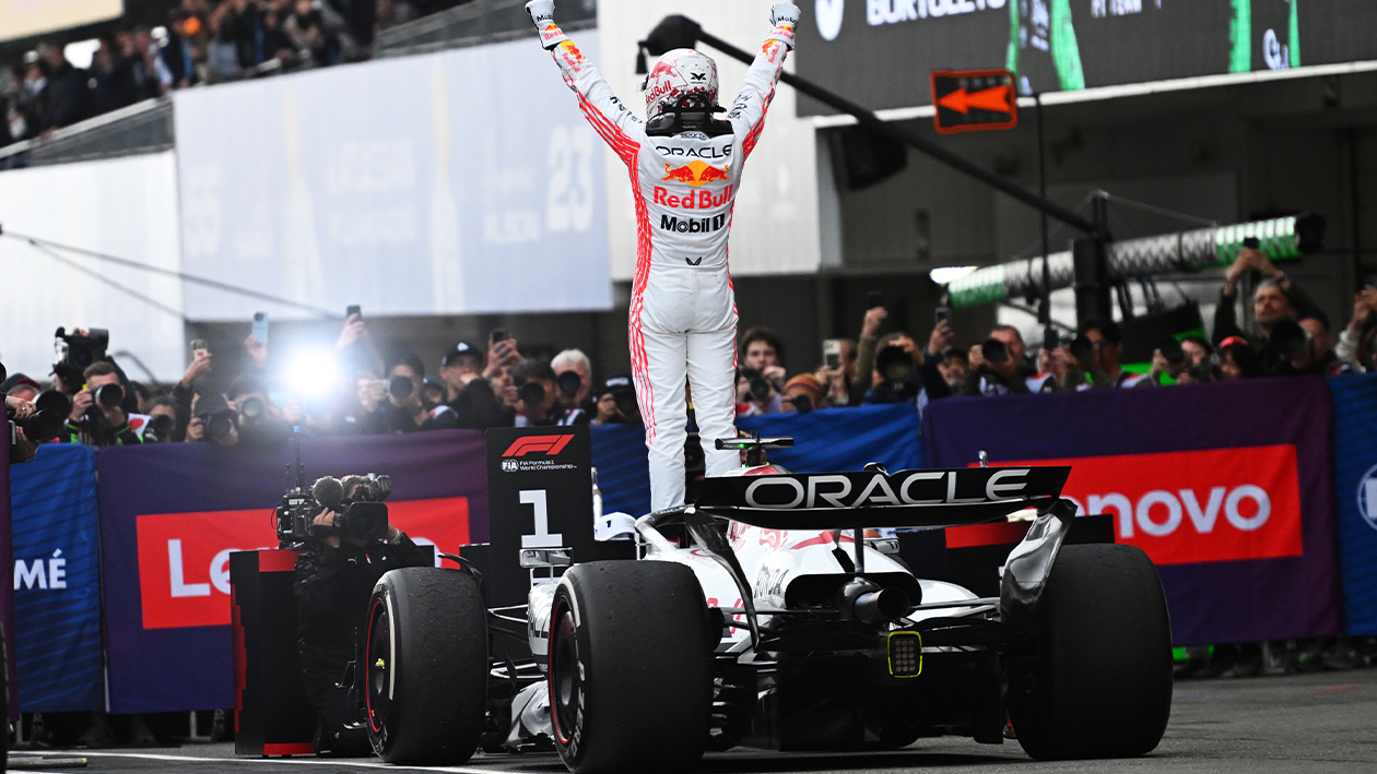 Max Verstappen stands on his Red Bull F1 car with fists raised after winning the 2025 Japanese Grand Prix