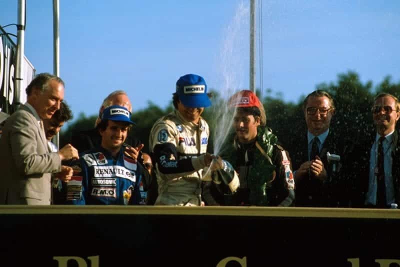 Winner Nelson Piquet sprays the champagne as 2nd place Alain Prost left, and Nigel Mansell, right look on.