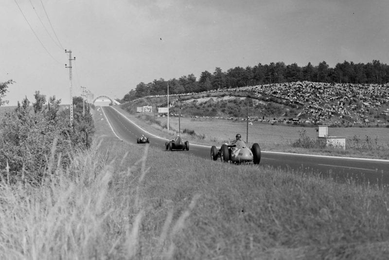 Jean Behra in a BRM P25, leads Stirling Moss in his Vanwall, and Juan Manuel Fangio's Maserati 250F.