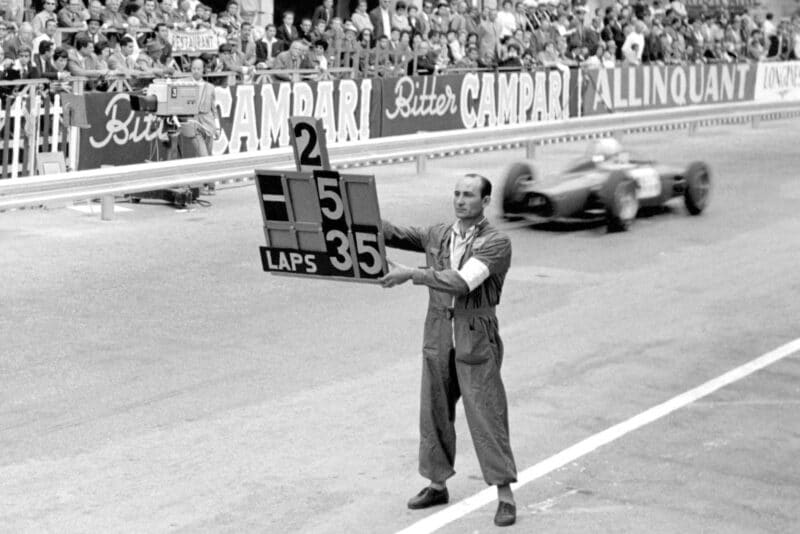 A mechanic shows Richie Ginther he is in 2nd place.