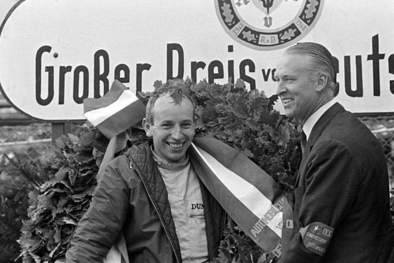John Surtees celebrates his maiden victory on the podium.