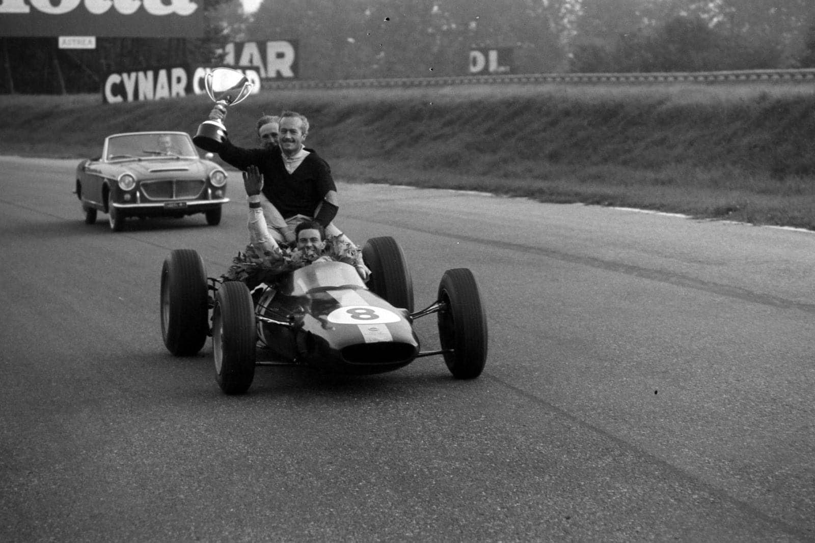 Jim Clark, Lotus 25 Climax, with Colin Chapman holding the winner's trophy on the back.