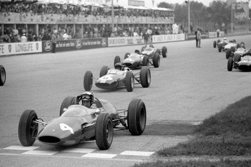 John Surtees, Ferrari 156 Aero, Jim Clark, Lotus 25 Climax, Lorenzo Bandini, Ferrari 156/63, Dan Gurney, Brabham BT7 Climax, and the rest of the field on the grid awaiting the start.