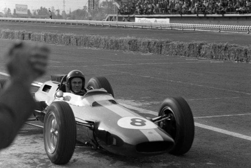Jim Clark, Lotus 25 Climax, pulls into the pitlane after the race.