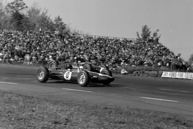 Jim Clark, Lotus 25 Climax, signals as he passes Jo Bonnier, Cooper T66 Climax.