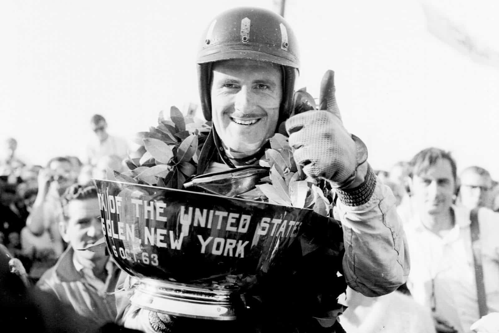 Graham Hill (BRM/Owen Racing Org.) celebrates his 1st position on the podium with a thumbs-up.
