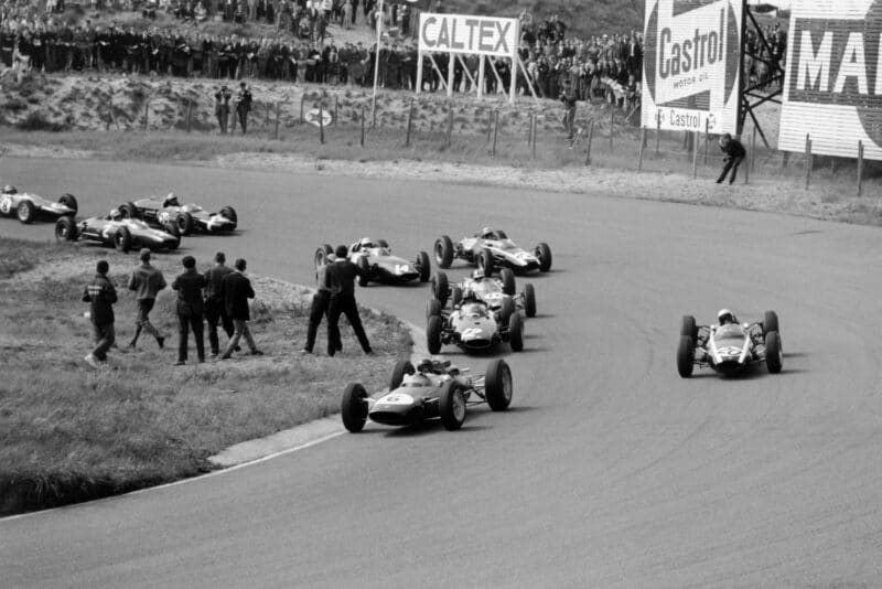 Jim Clark (#6 Lotus 25-Climax) leads Bruce McLaren (#20 Cooper T66-Climax), Graham Hill (#12 BRM P57), Jack Brabham (#16 Brabham BT7-Climax), Tony Maggs (#22 Cooper T66-Climax), Richie Ginther (#14 BRM P57), John Surtees (#2 Ferrari 156), Jo Bonnier (#28 Cooper T60-Climax) and Trevor Taylor (#8 Lotus 25-Climax) into Tarzan Corner at the start.