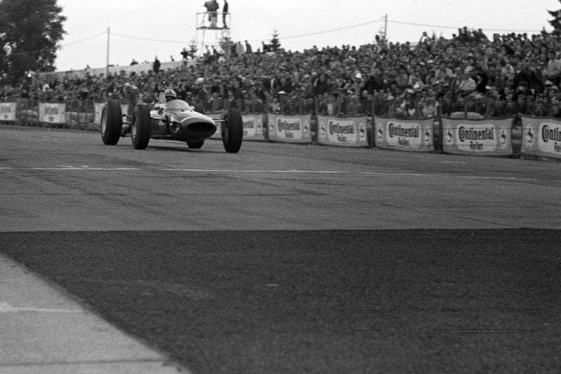 John Surtees, Ferrari 158, celebrates as he crosses the finish line for victory.