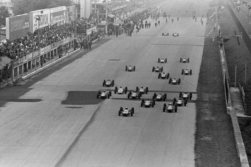 The start of the race. Bruce McLaren, Cooper T73 Climax, John Surtees, Ferrari 158, and Dan Gurney, Brabham BT7 Climax, do battle at the front.