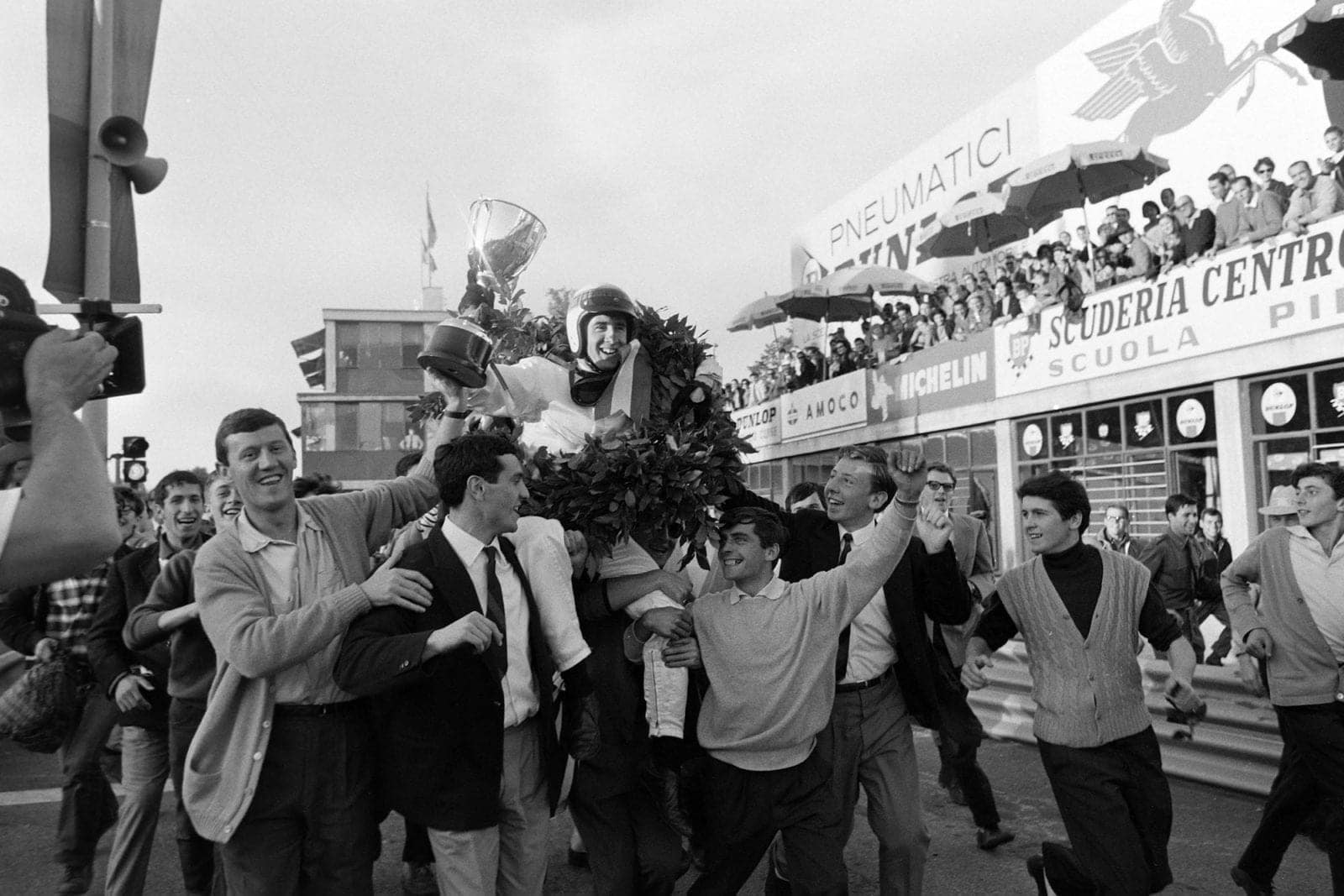 Race winner Jackie Stewart is carried through the pit lane after the podium celebration.