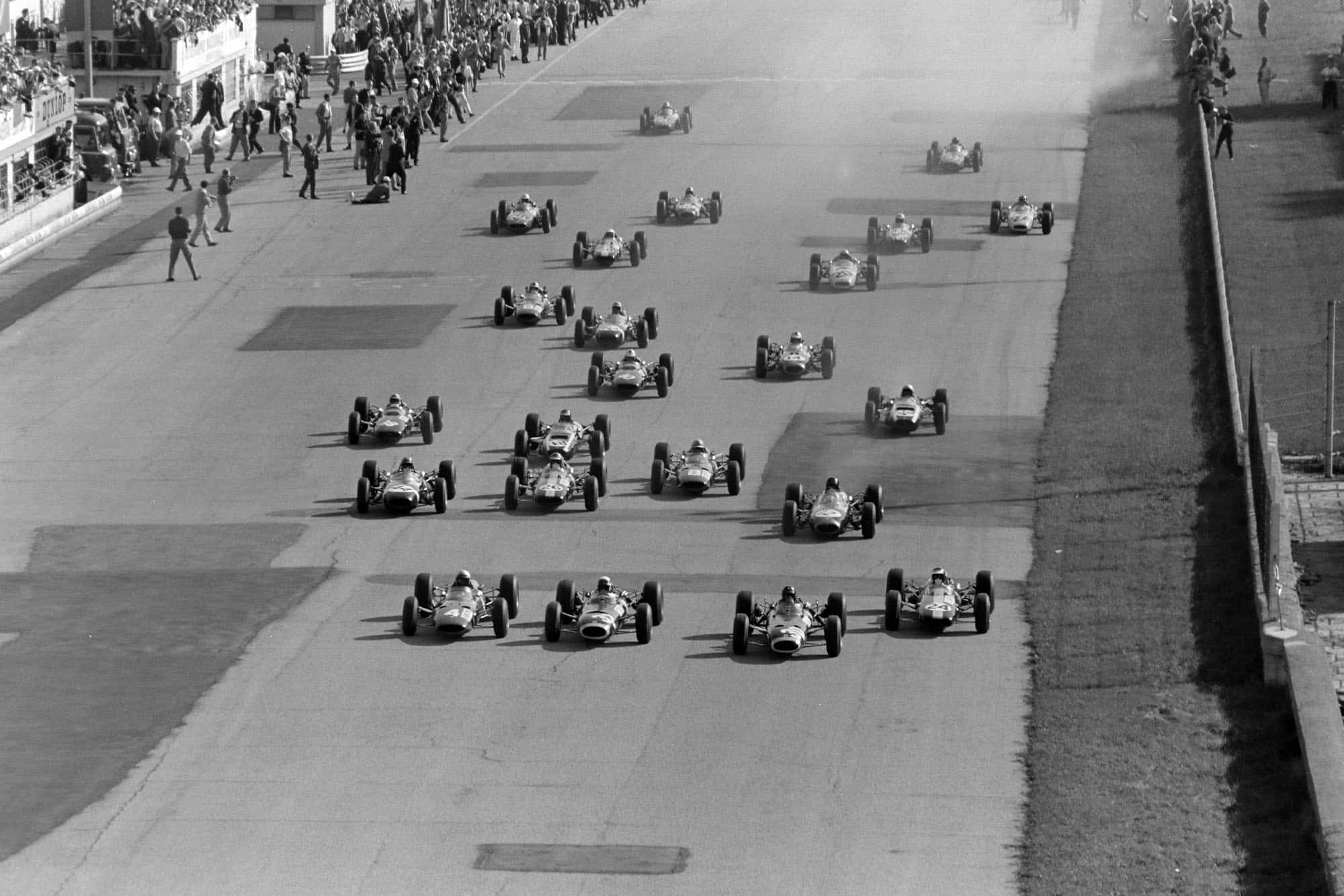 The start of the race. Lorenzo Bandini, Ferrari 1512, battles with Jackie Stewart, BRM P261, Graham Hill, BRM P261, and Jim Clark, Lotus 33 Climax, heading towards the first turn.