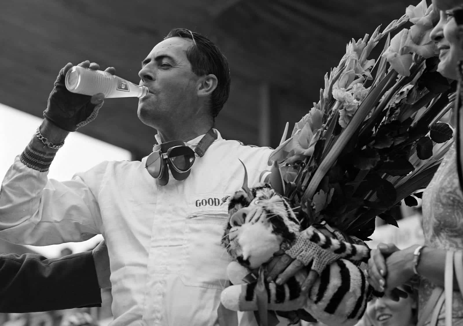 Race winner Jack Brabham celebrates with a drink on the podium.