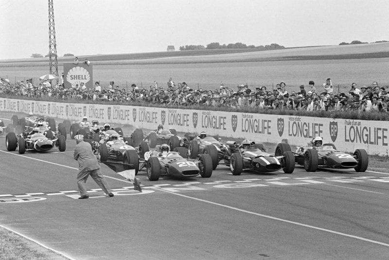 The race begins as the French Tricolore is waved, with Lorenzo Bandini, Ferrari 312, John Surtees, Cooper T81 Maserati and Mike Parkes, Ferrari 312 on the front row.