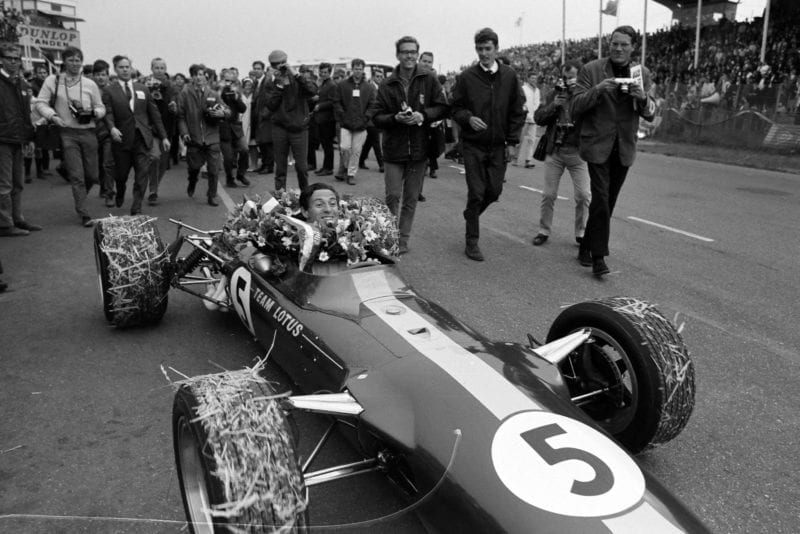 Race winner Jim Clark arrives in the pit lane in his Lotus 49 Ford. His tyres are covered in hay.
