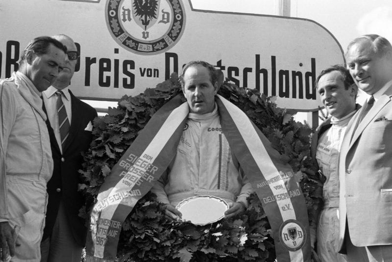 Race winner Denny Hulme on the podium with Jack Brabham, 2nd position, and Chris Amon, 3rd position.
