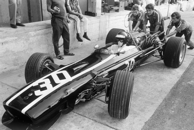 Engineers push the car of Jochen Rindt, Cooper T86 Maserati, in the pits.
