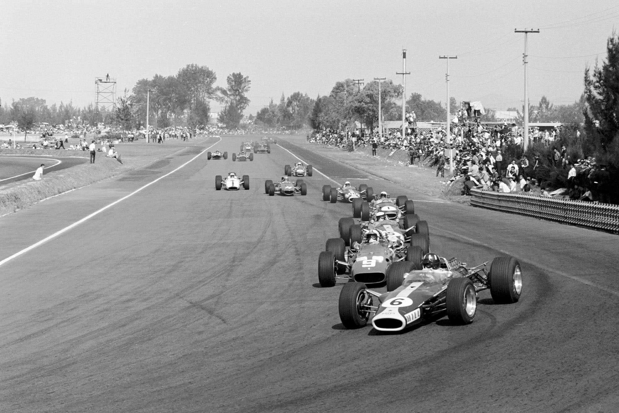 In the opening lap of the race, Graham Hill (GBR) Lotus 49 leads Chris Amon (NZL) Ferrari 312 with race winner Jim Clark (GBR) Lotus 49 in third place. Mexican Grand Prix, Mexico City, 22 October 1967.