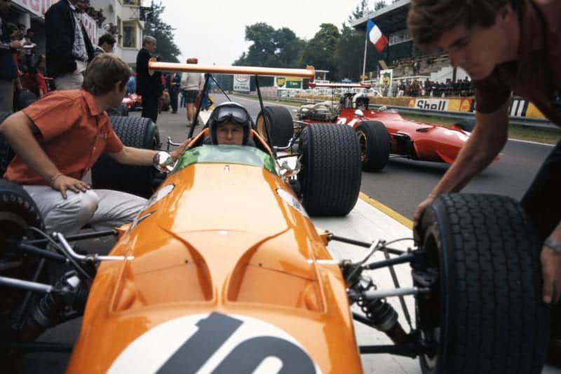 Bruce McLaren, McLaren M7A Ford, getting new tyres while Chris Amon, Ferrari 312, leaves the pits.