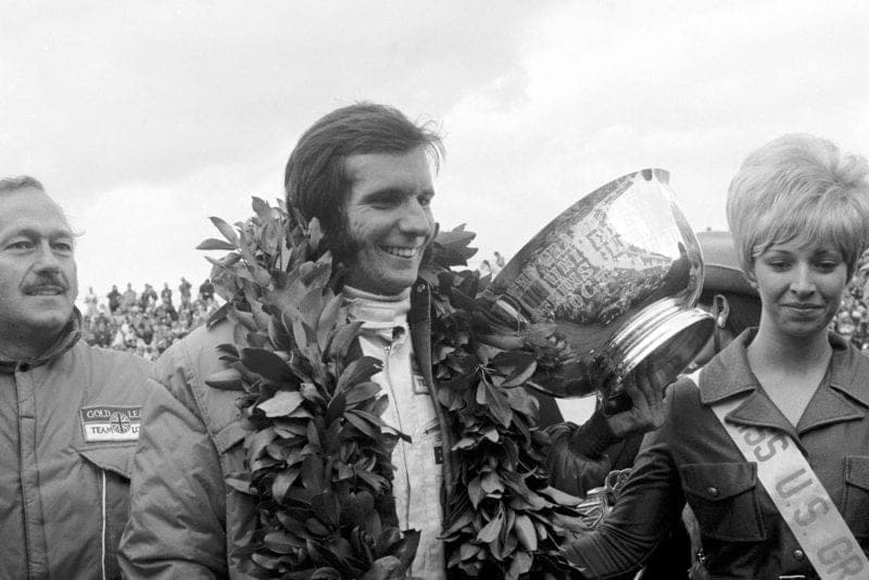 Emerson Fittipaldi celebrates on the podium after winning the 1970 United States Grand Prix