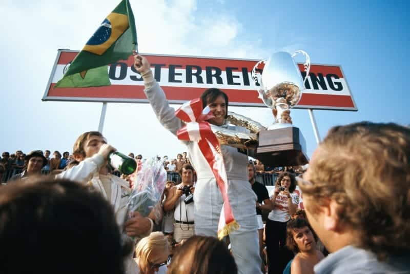 Emerson Fittipaldi holds his trophy and the Brazilian flag aloft after winning the 1972 Austrian Grand Prix.