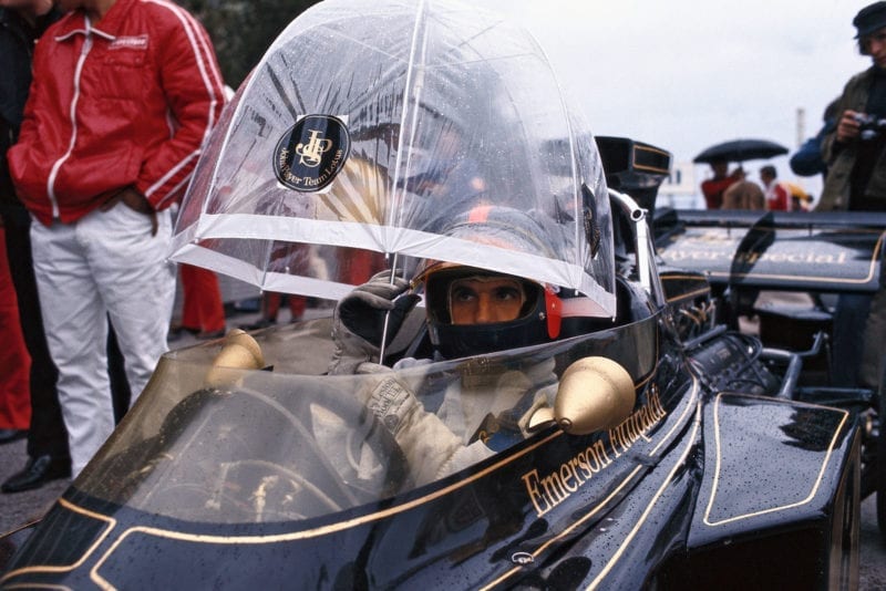 Emerson Fittipaldi uses an umbrella for cover whilst sitting in his car waiting for the 1972 Monaco Grand Prix to start.