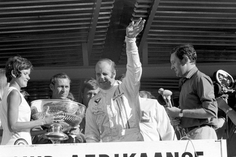 Denny Hulme waves from the podium after winning the 1972 South African Grand Prix.