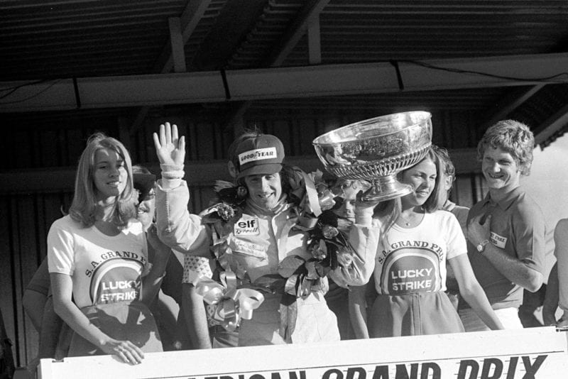Jackie Stewart waves to the crowd from the podium after winning the 1973 South African Grand Prix for Tyrrell.
