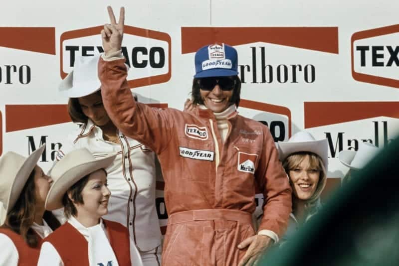 Emerson Fittipaldi (McLaren) gives a V for victory on the podium at the 1974 Belgian Grand Prix, Zolder.