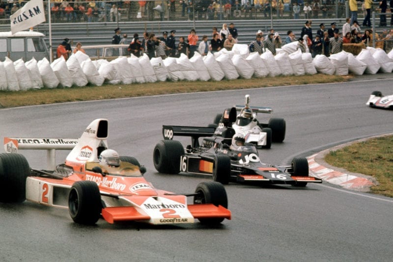 Jochen Mass (McLaren, foreground) and Tom Pryce (Shadow) attempt to get to grips with the slippery conditions at the 1975 Dutch Grand Prix, Zandvoort.