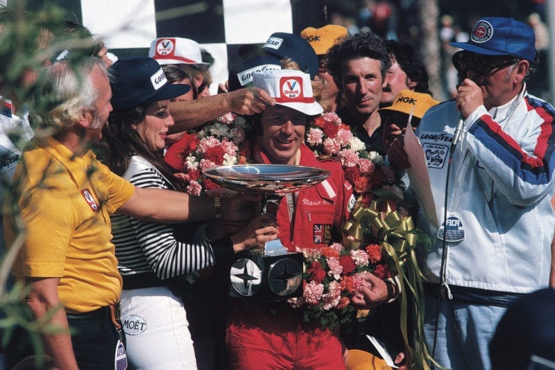 Mario Andretti (Lotus) celebrates on the podium after winning the 1977 United States Grand Prix West, Long Beach.