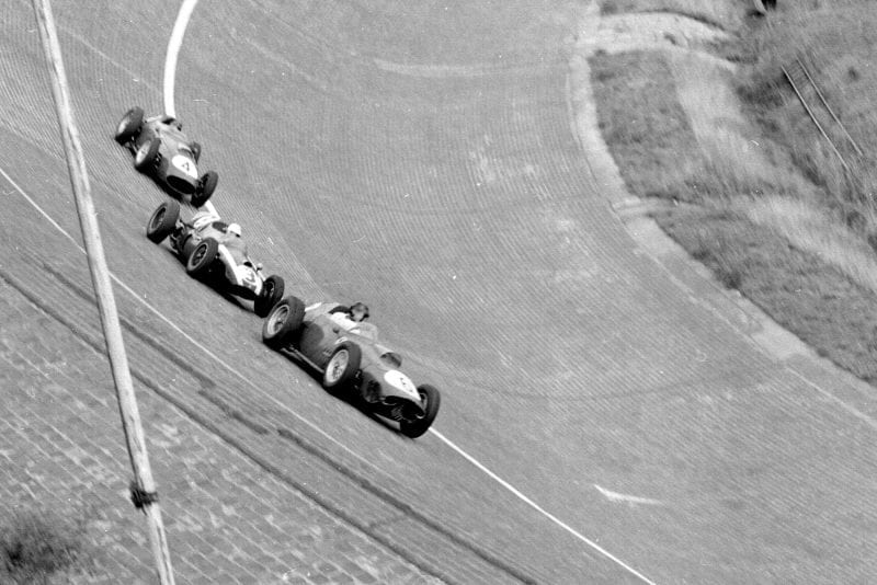Dan Gurney in a Ferrari Dino 246 leads Masten Gregory driving a Cooper T51 Climax and Tony Brooks in a Ferrari Dino 246 on the North Turn.