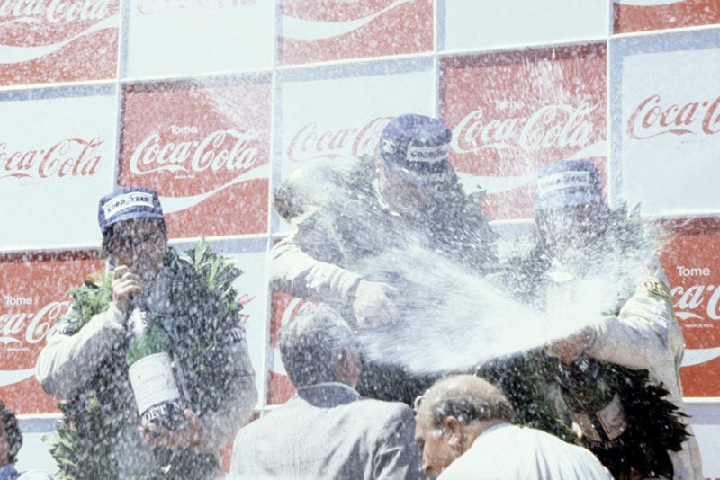 Alan Jones (Williams FW07-Ford Cosworth), 1st position and Nelson Piquet (Brabham BT49-Ford Cosworth), 2nd position, and Keke Rosberg (Fittipaldi F7-Ford Cosworth), 3rd position on the podium.