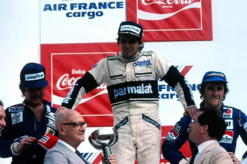 On the podium, 1st Nelson Pique (centre), 2nd Keke Rosberg (lef), 3rd Alain Prost (right). An exhausted Piquet supports himself on the shoulders of Rosberg and Prost before collapsing.