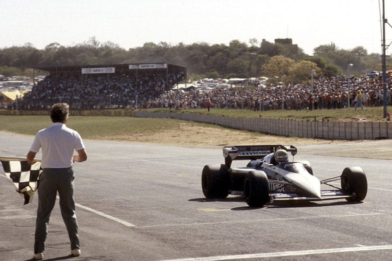 Riccardo Patrese takes the chequered flag.