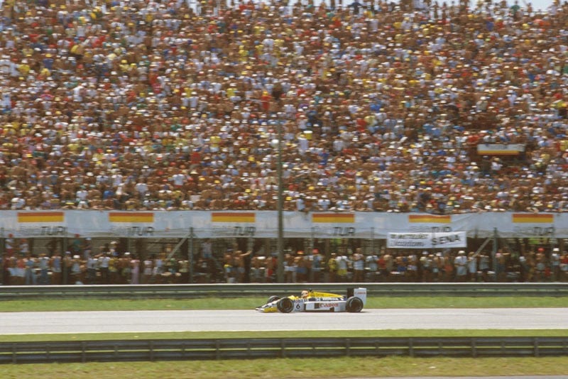 Nelson Piquet (Williams FW11 Honda)passes a packed grandstand.