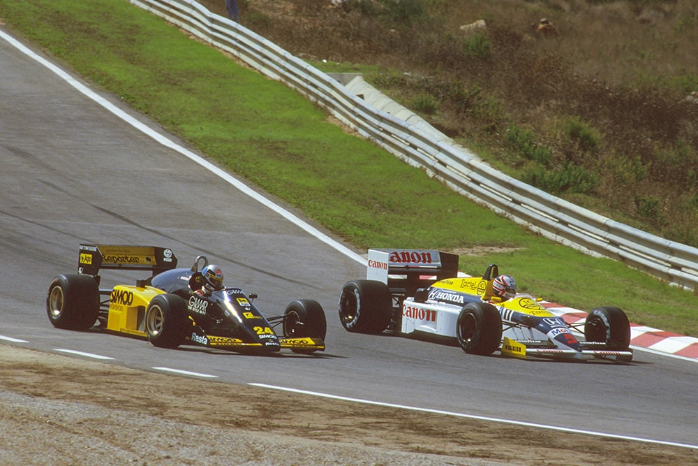 Nigel Mansell in aWilliams FW11 Honda laps Alessandro Nannini driving a Minardi M185B Motori Moderni.