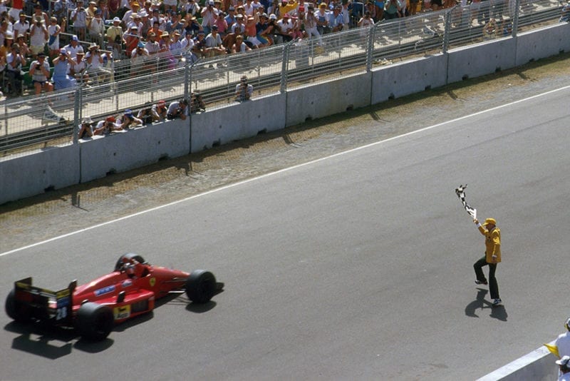 Gerhard Berger takes the chequered flag in his Ferrari F187 and celebrates another win.