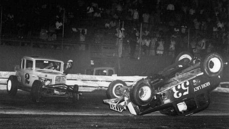 AJ FOYT HOUSTON, TX - 1956- A.J. Foyt climbs out of his first modified car at Playland Speedway after a tangle with Billy Wade. M.J. Burton is barely visible behind the fence.