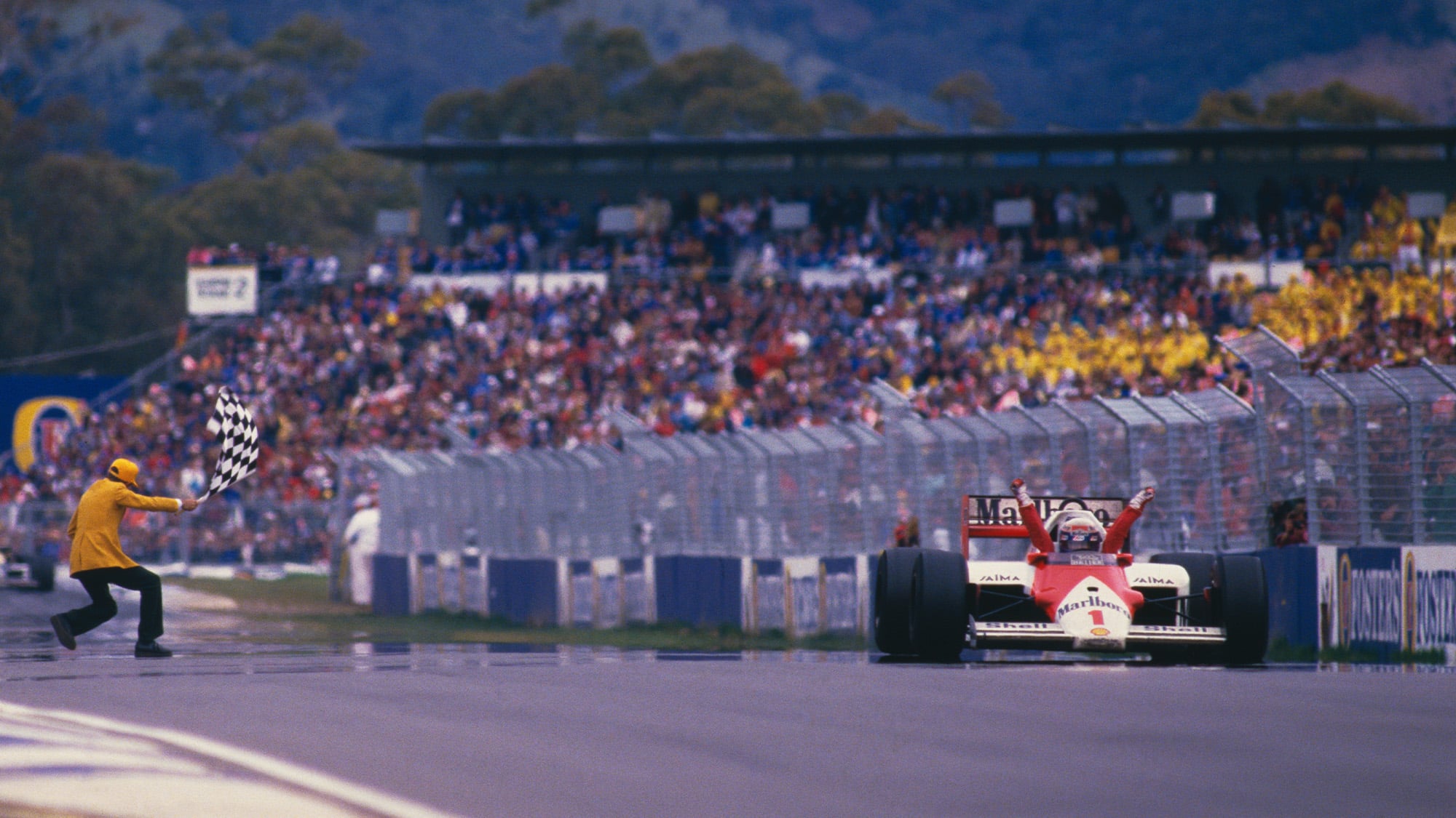 Alain Prost raises his arms in the air as he crosses the finish line at Adelaide to win the Australian Grand Prix and 1986 world championship