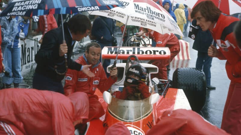 Bernie Ecclestone with Teddy Mayer and Alistair Caldwell around James Hunt in cockpit of McLaren