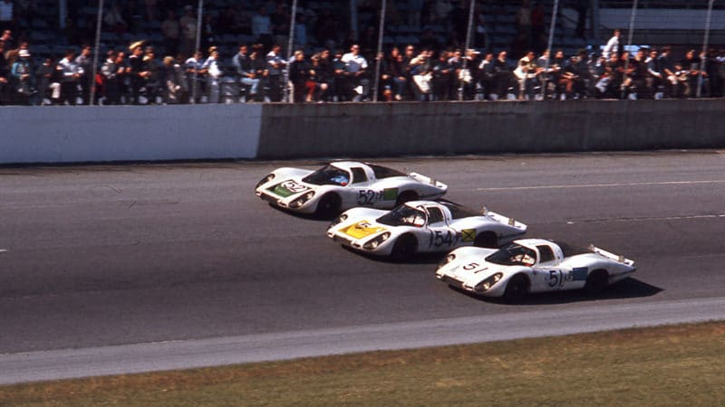 DAYTONA BEACH, FL - FEBRUARY 4, 1968: German factory Porsche 907s swept the top three spots in the 24 Hours of Daytona at Daytona International Speedway and crossed the finish line in three-abreast formation at the checkered flag. The No. 54 was the race winner. It was initially assigned to drivers Vic Elford and Jochen Neerspach, but they were joined later by Rolf Stommellen, whose 907 crashed out at dusk. Jo Siffert and Hans Herrmann drove the No. 52 car, but also took turns driving the No. 54 so they could share in the victory. To make things even more complicated, Stommellen’s teammate Gerhard Mitter moved over to the Siffert/Herrman car and drove it during the final hours as that car ultimately finished second. The third place No. 51 was steered by Jo Schlesser and Joe Buzzetta. (Photo by ISC Images & Archives via Getty Images)