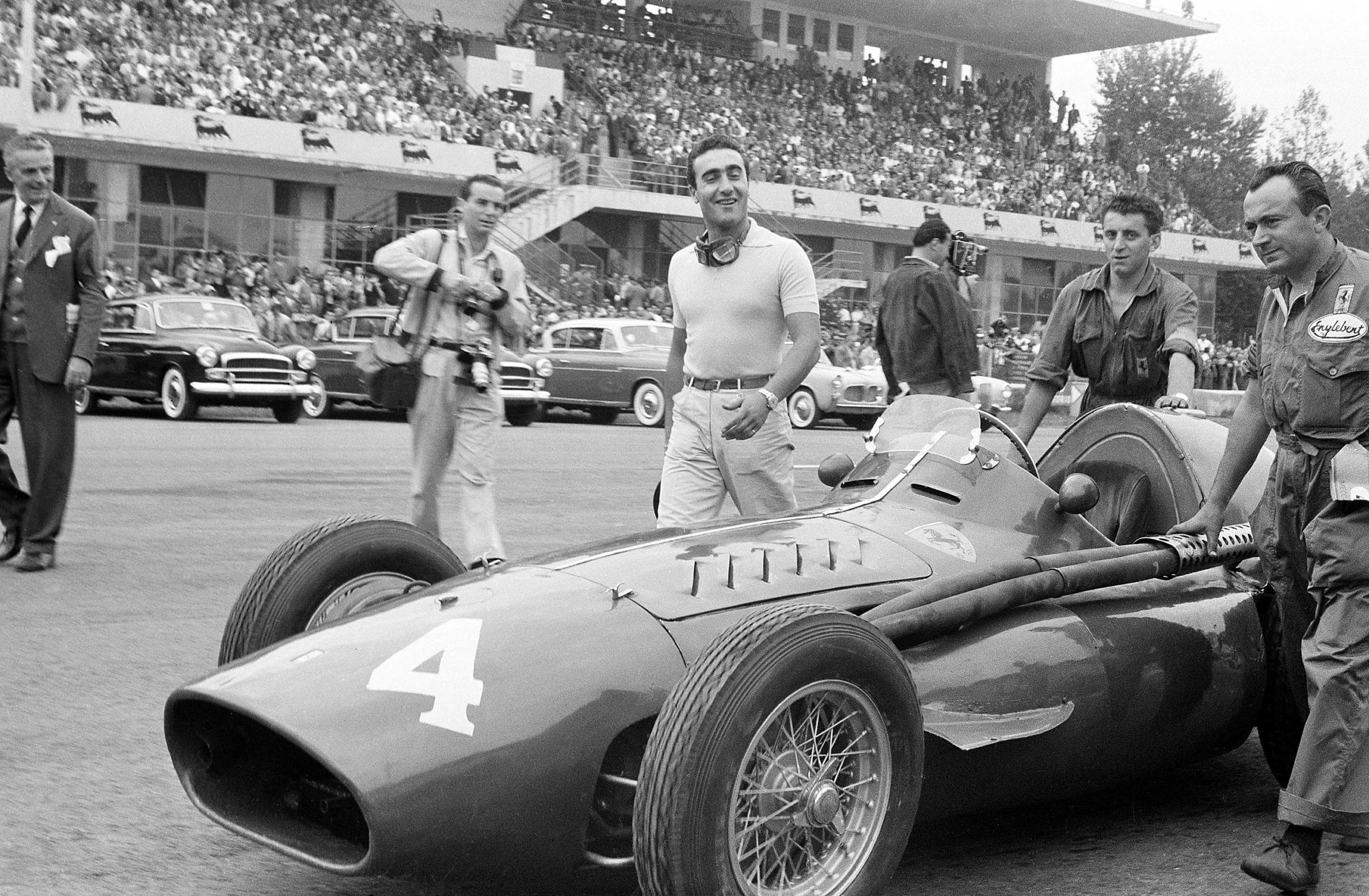 Racing driver Eugenio Castellotti with his Ferrari 'Squalo' walking to the grid before the start of the Italian Grand Prix at Monza, 11th September 1955. The man with all the cameras is the well-known photo-journalist Bernard Cahier. (Photo by Klemantaski Collection/Getty Images)