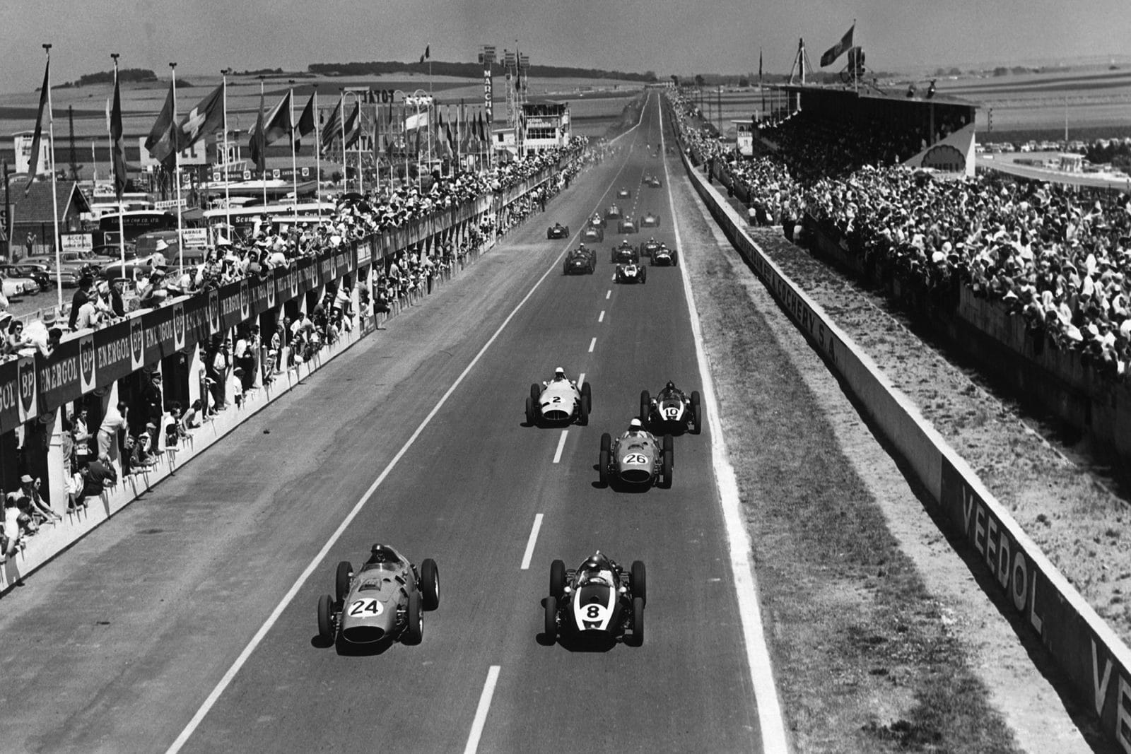 Tony Brooks, #24 Ferrari Dino 246 and Jack Brabham in a Cooper T51-Climax lead at the start.