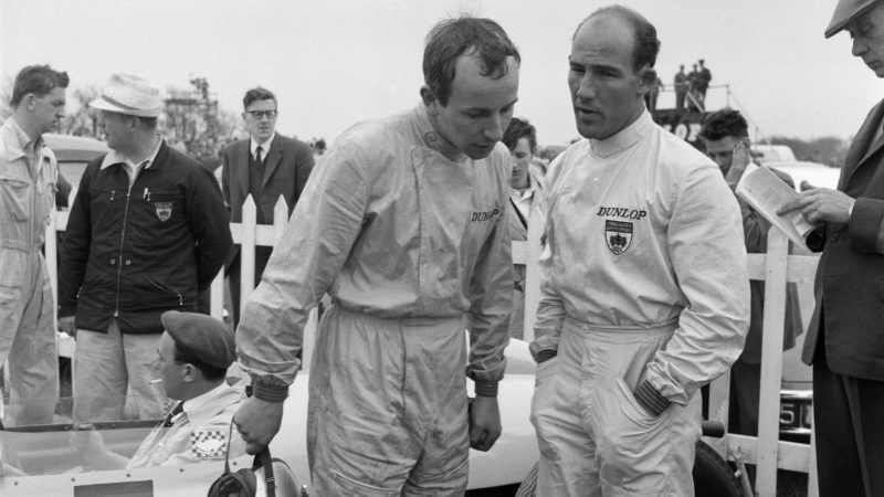 Motor races at Goodwood. Ace racing driver Stirling Moss had a miracle escape from death when he crashed at 120 miles an hour. Pictured, Moss chatting to one of the other drivers, 23rd April 1962. (Photo Cooper/Mirrorpix/Getty Images)