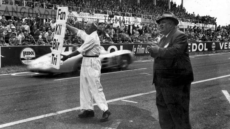 17th July 1954: Alfred Neubauer, team manager of Mercedes Benz instructs a mechanic to signal to the two Mercedes during a French Grand Prix at Reims. It was the first time German cars had competed for 15 years. Original Publication: Picture Post - 7209 - First Race Of The Mercedes - A Ruthless Triumph - pub. 1954 (Photo by Joseph McKeown/Picture Post/Hulton Archive/Getty Images)