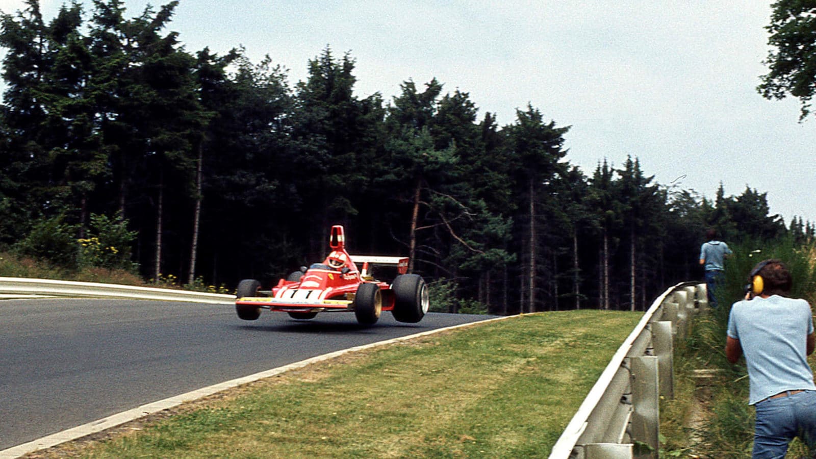 Spectators watch Ferrari of Clay Regazzoni launching off the ground at Nurburgring in 1976