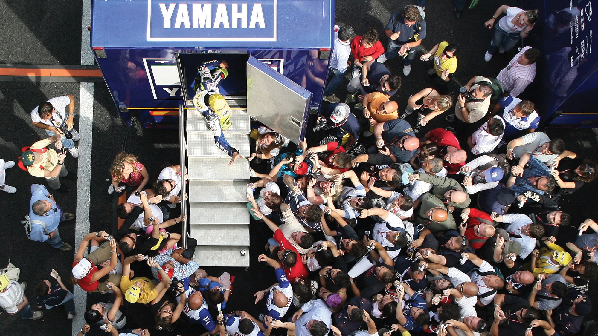 Valentino Rossi waves at a paddock crowd from his motorhome