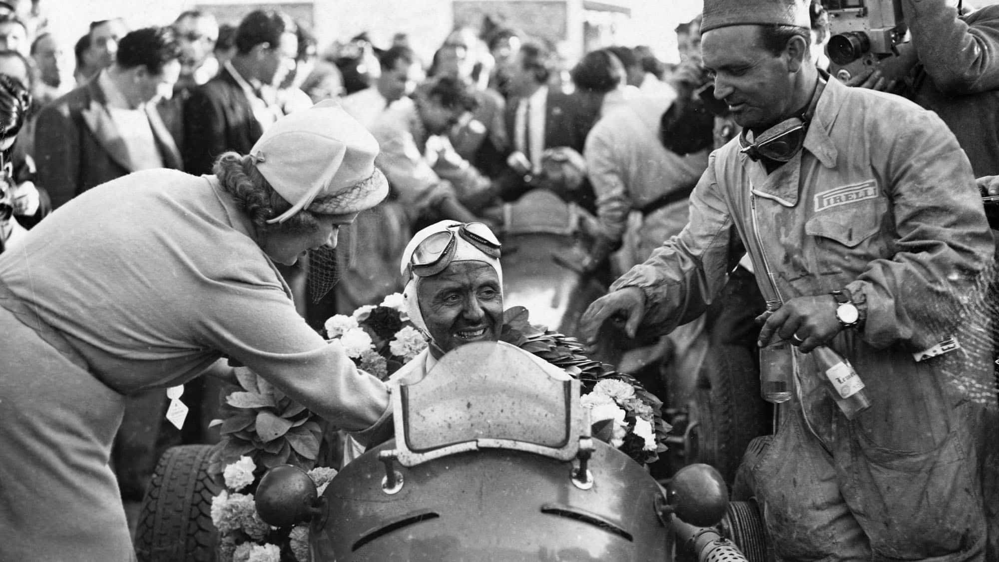Lady Howe puts a wreath around Luigi Villoresi in his Maserati racecar after he won the International Grand Prix. (Photo by © Hulton-Deutsch Collection/CORBIS/Corbis via Getty Images)